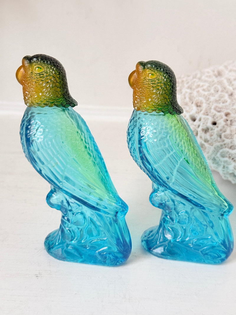 Pair of vintage Avon turquoise glass parrot bottles with green amber stoppers photographed on a white surface