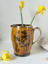 Antique Ridgways stoneware jug photographed on a white surface in amber treacle glaze with black Coaching Days and Coaching Ways transfer scenes and silver tone handle
