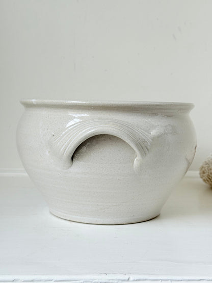 Large studio pottery bowl with hand-painted grape motif and side handles, photographed on a white surface