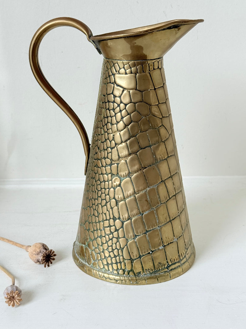 Vintage brass jug with alligator patterned surface, photographed against a white background.