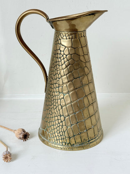 Vintage brass jug with alligator patterned surface, photographed against a white background.