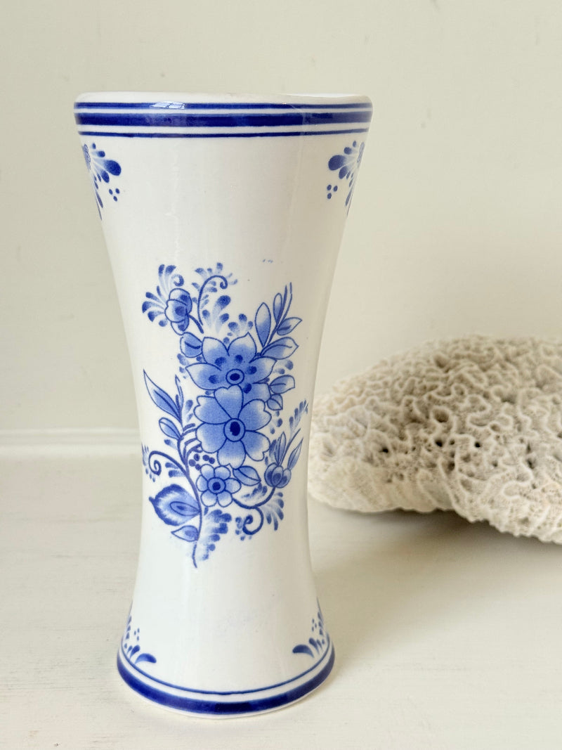 Blue and white Delft hand painted ceramic vase with windmill and floral decoration, photographed on white surface.
