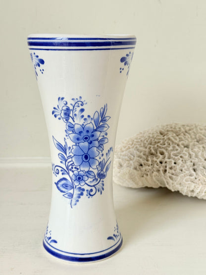 Blue and white Delft hand painted ceramic vase with windmill and floral decoration, photographed on white surface.