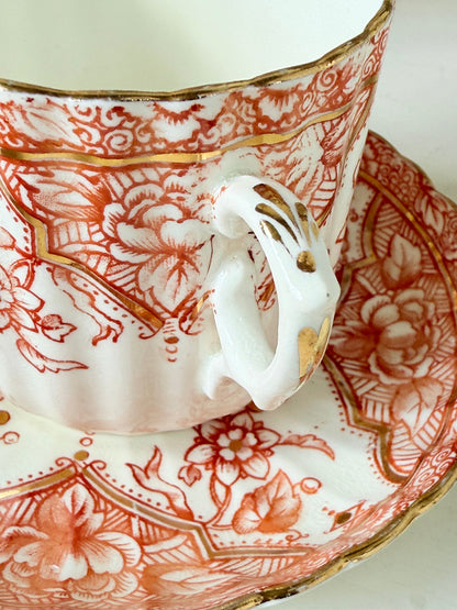 Vintage coral transferware coffee cans and saucers with scalloped edges and gold accents, set of ten, styled on a white surface.