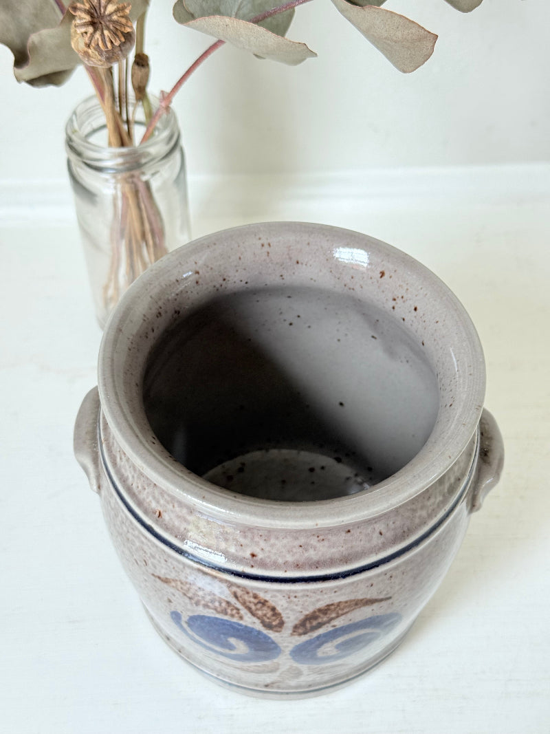 Vintage stoneware confit pot with blue and brown folk art design, photographed on a white surface