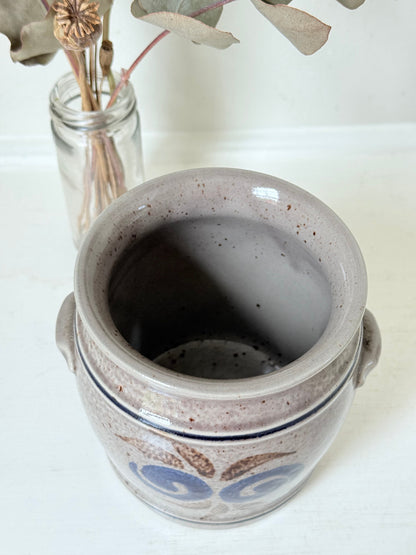 Vintage stoneware confit pot with blue and brown folk art design, photographed on a white surface