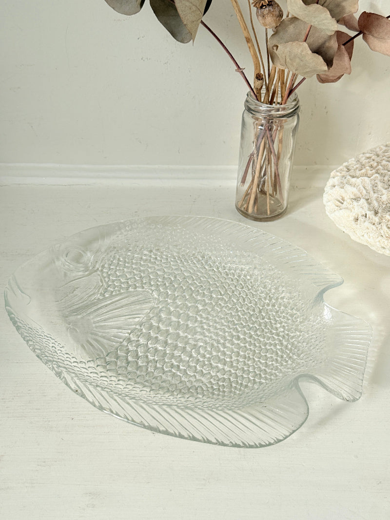 Vintage clear glass fish shaped serving dish with textured scale pattern photographed on a white surface
