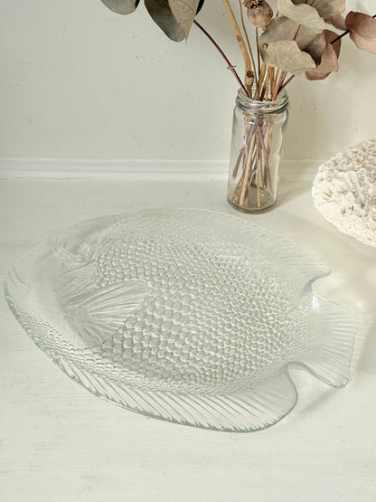 Vintage clear glass fish shaped serving dish with textured scale pattern photographed on a white surface