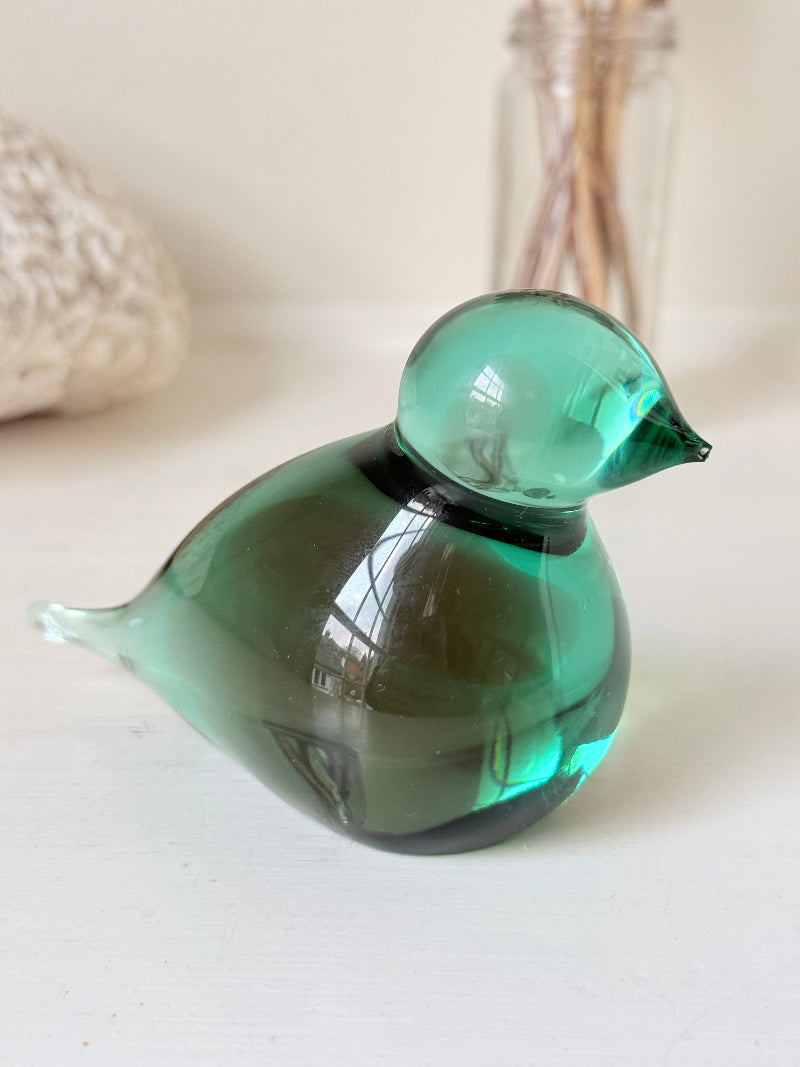 Vintage green glass bird paperweight photographed on a white surface