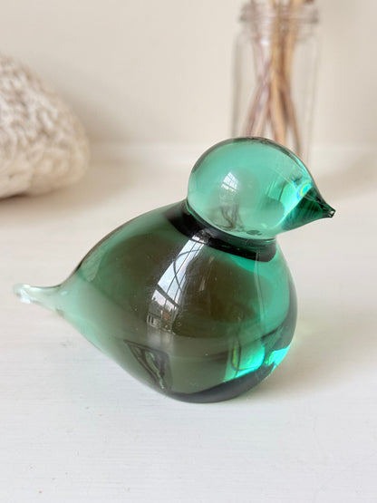Vintage green glass bird paperweight photographed on a white surface