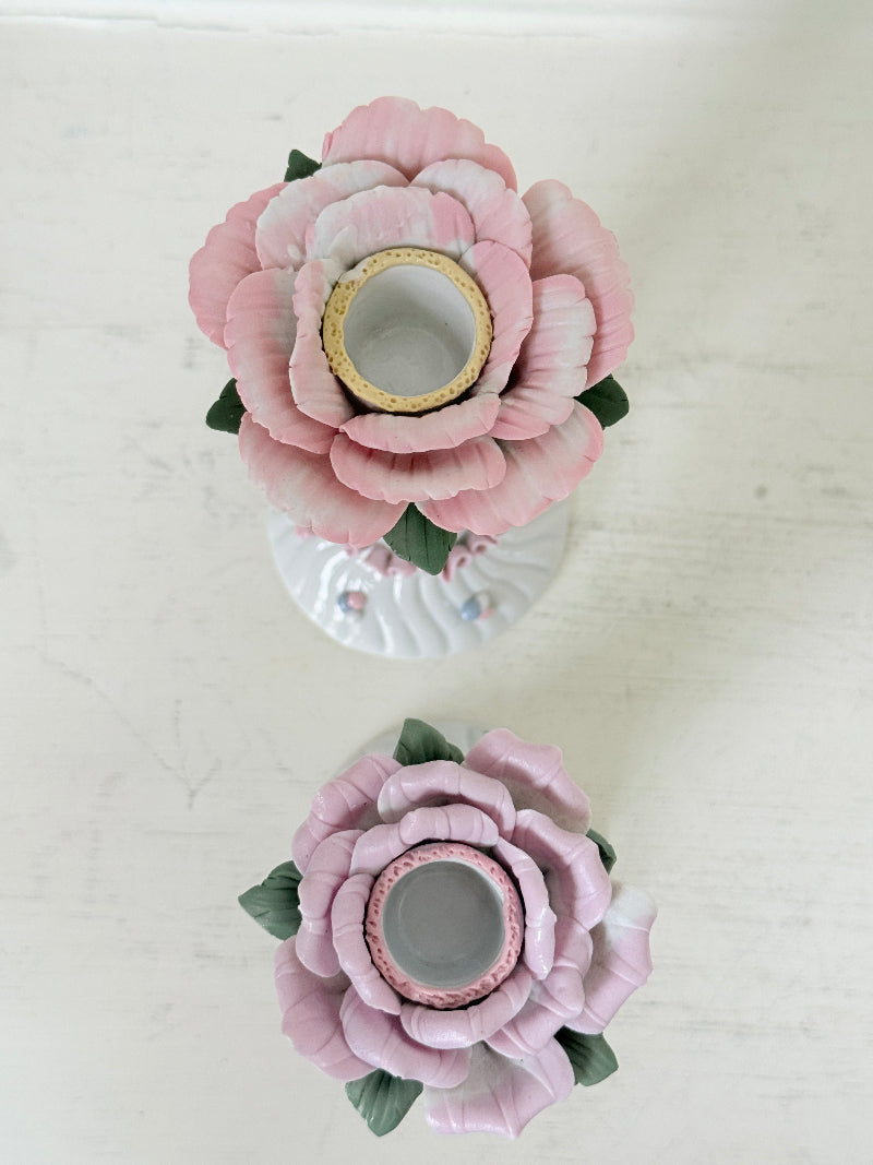 Pair of vintage floral ceramic candlesticks with rose candle cups and pink taper candles styled on a white surface