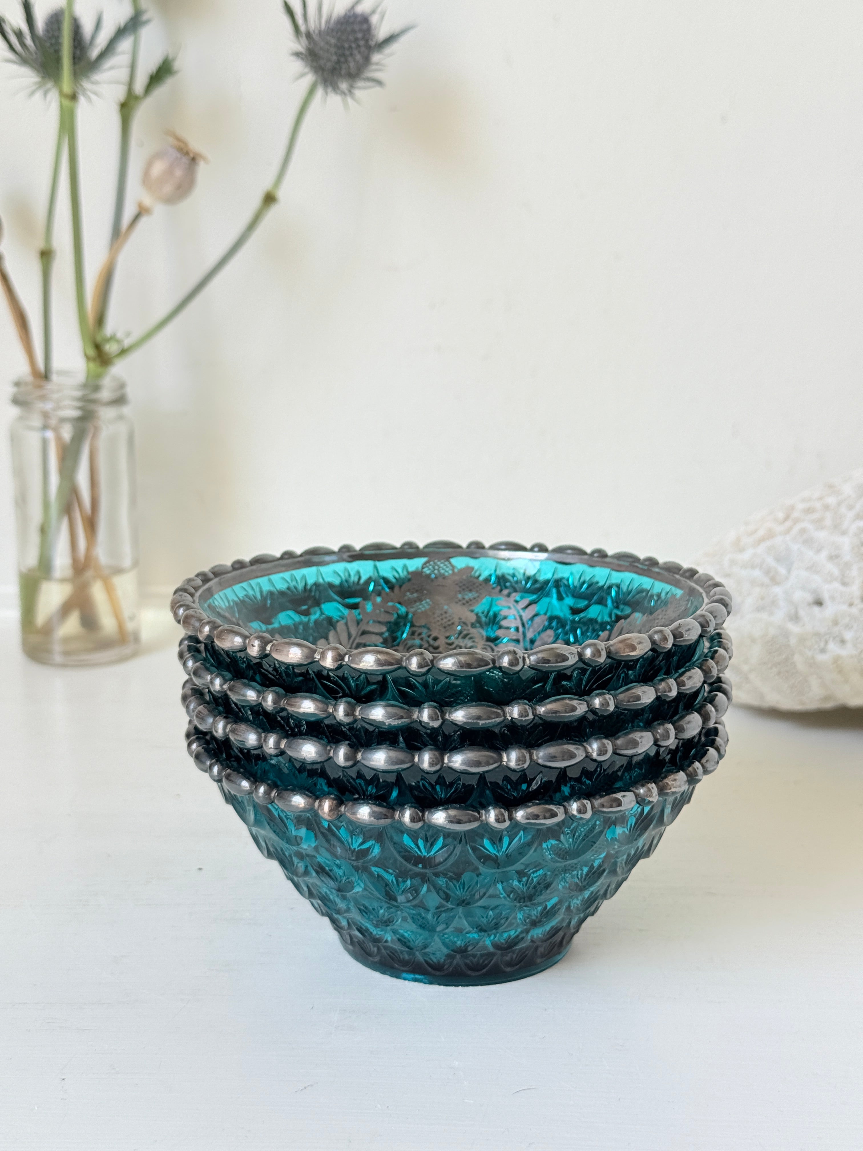 Set of four vintage teal pressed glass dessert bowls with gilt floral decoration, photographed on a white surface