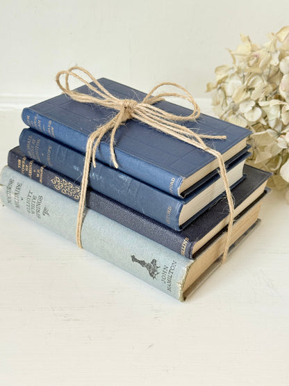 Vintage decorative book bundle in navy, grey, and cream tied with twine, photographed on a white surface