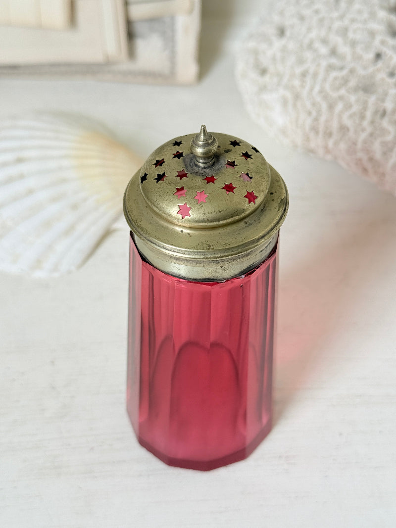 Antique cranberry glass sugar shaker with ribbed optic body, pierced metal top, star holes and deep pink glass