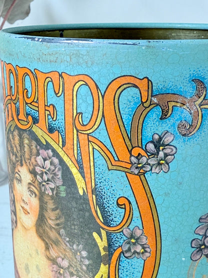 Vintage turquoise and gold metal sweet tin with Art Nouveau woman portrait photographed on a white surface.