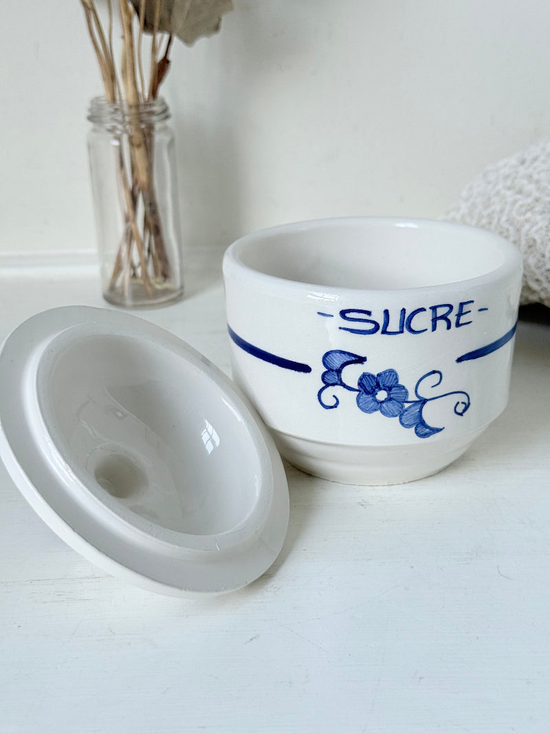 Vintage French blue and white studio pottery sugar bowl with lid, photographed on a white surface.