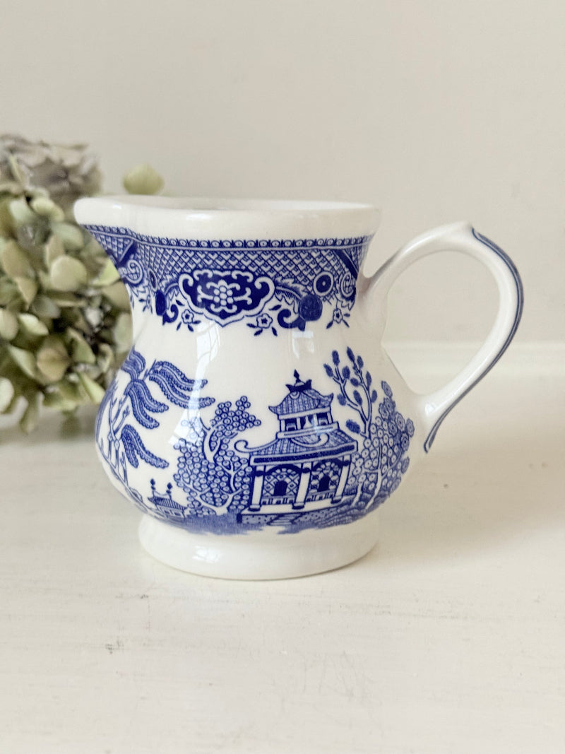 Vintage Churchill Blue Willow milk jug in blue and white ceramic photographed on a white surface.