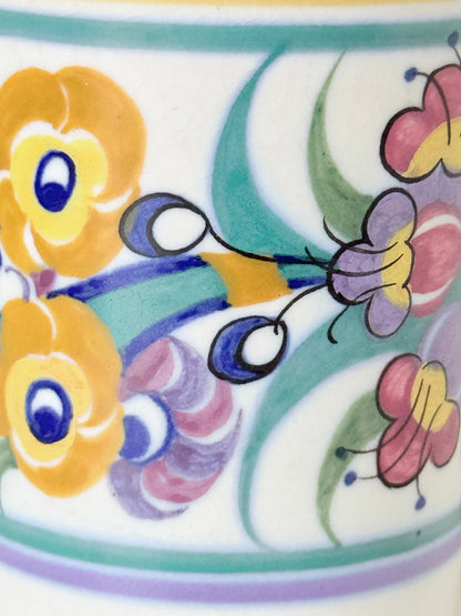 Vintage Poole Pottery pen pot with colourful floral design photographed on a white surface