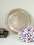 Vintage round silver plate tray with brass rim, pierced edge and etched central motif, photographed on white surface
