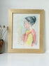 Vintage pastel portrait of a woman in profile wearing red and yellow, framed under glass, photographed on a white surface