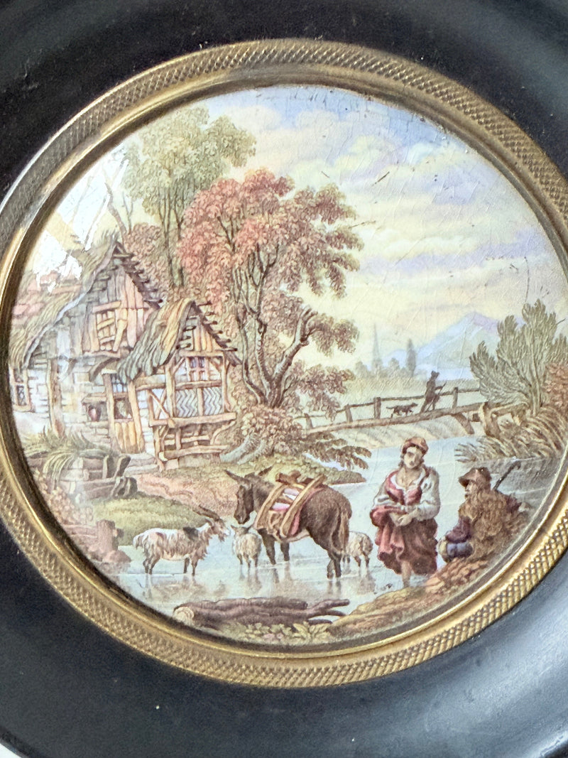 Antique Prattware framed pot lid with cottage scene photographed on a white surface.