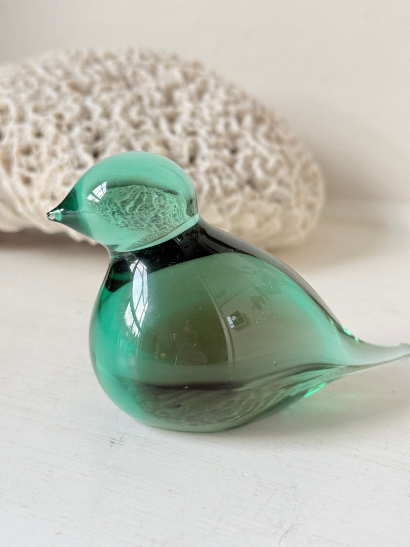 Vintage green glass bird paperweight photographed on a white surface