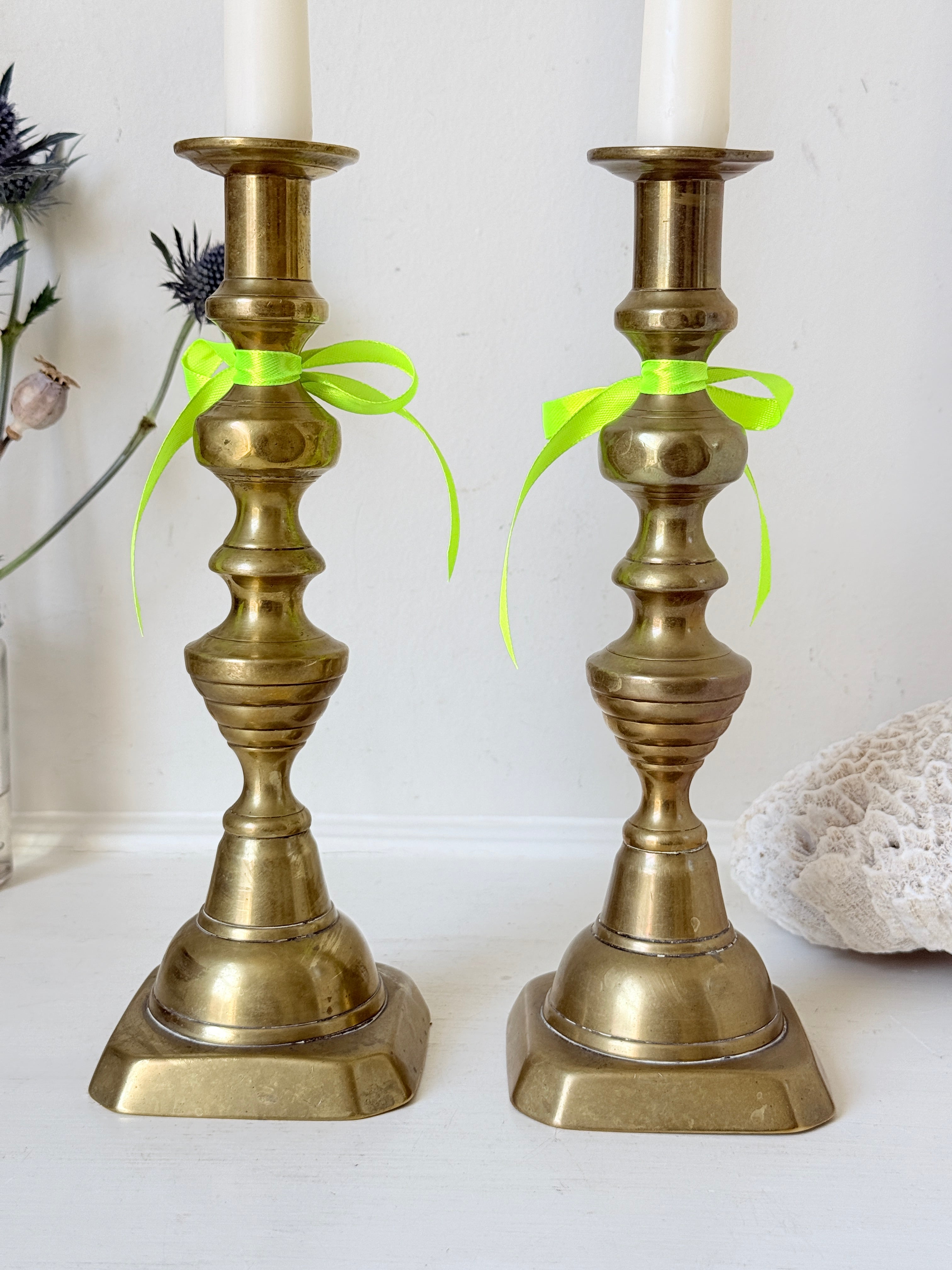 Pair of vintage brass candlesticks with turned stems and square bases, photographed on a white surface
