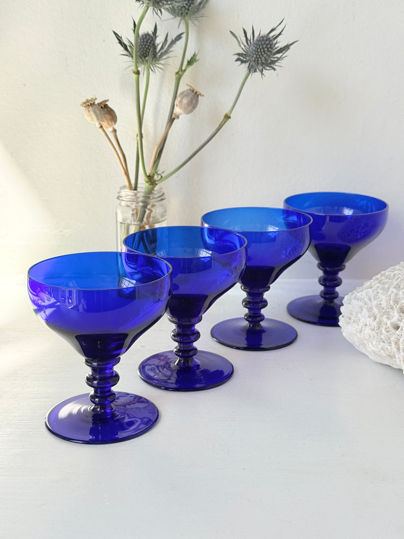 Set of four vintage cobalt blue cocktail glasses with stepped stems, photographed on a white surface