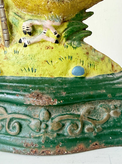 Close-up detail of a decorative ceramic figurine showing a yellow upper section with a small white animal figure, green textured lower section, and weathered painted finish.