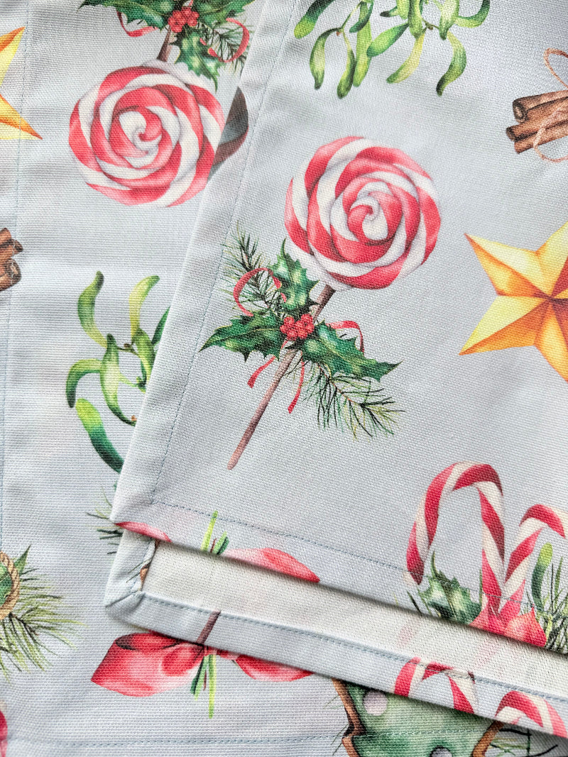 Blue Loft Christmas cotton tea towel with red striped stocking and festive motif pattern photographed on a white worktop.