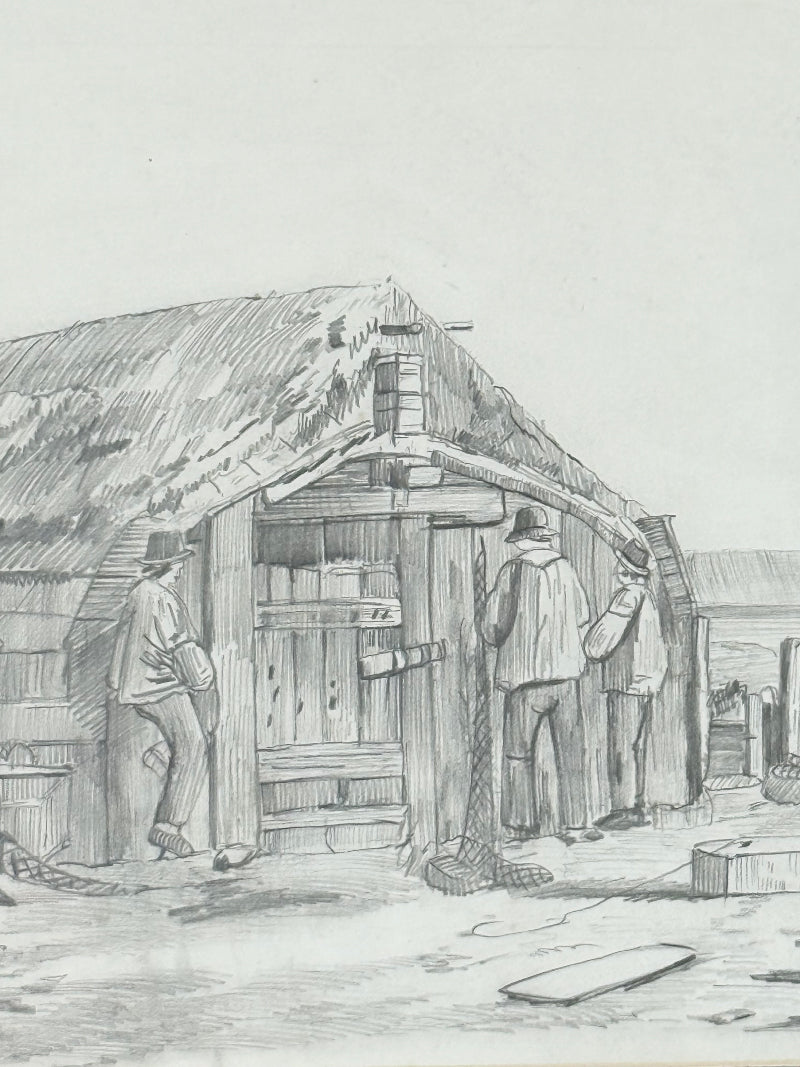 Vintage pencil drawing of rural scene with outbuildings and figures, under glass in black wooden frame, photographed on white surface.