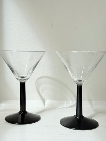 Set of six clear martini glasses with black stems, photographed on a white surface