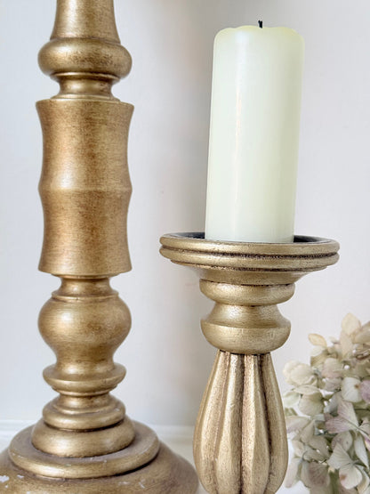 Pair of vintage wooden candlesticks, one tall and one small, in golden-toned finish, styled with pillar candles on a white surface.