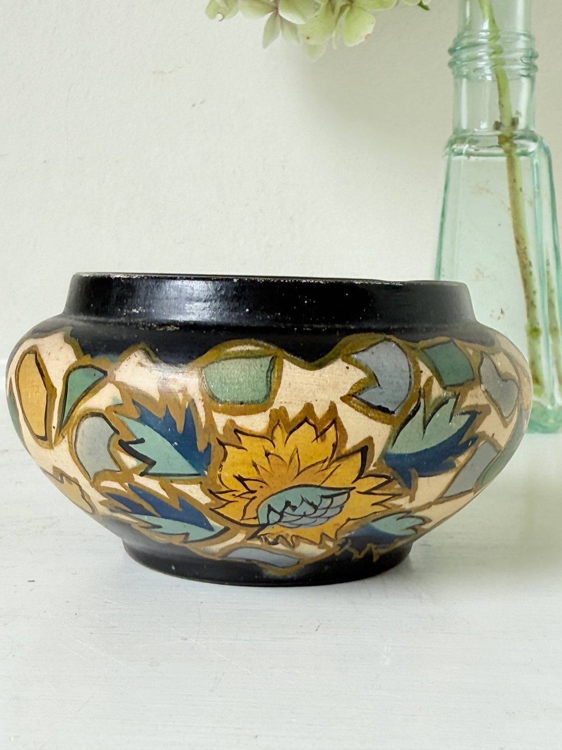 Brentleigh Ware Art Deco pottery jar with hand painted floral decoration on a black ground, photographed on a white surface