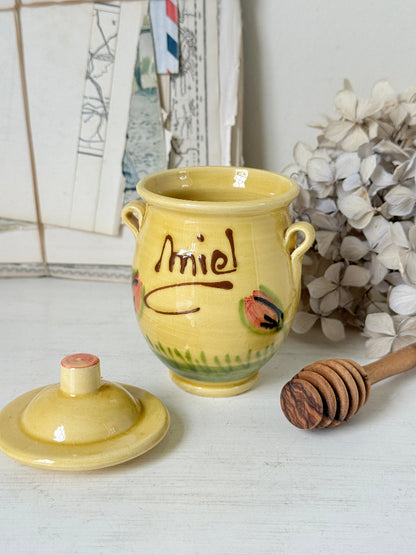 A yellow ceramic honey pot with a matching lid, decorated with the name &