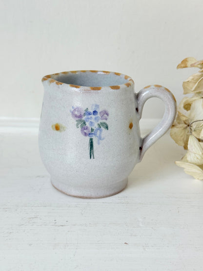 vintage studio pottery milk jug with hand painted lilac flowers and ochre rim photographed on white surface