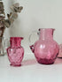 Vintage cranberry glass jugs, a pair with clear handles, photographed on a white surface