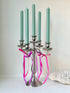 Five arm pewter style metal candelabra with aged silver finish styled with blue green taper candles on white surface