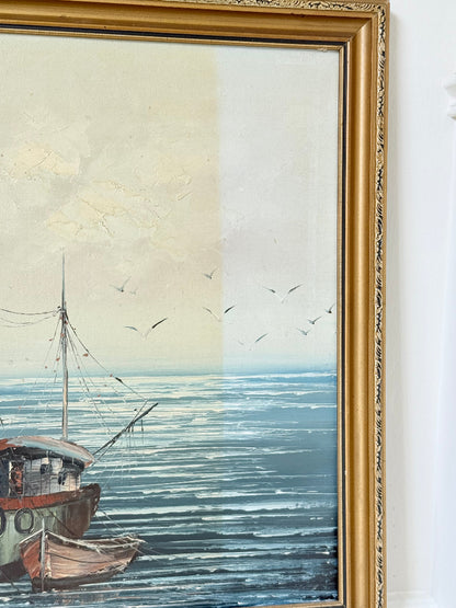 Vintage harbour scene oil painting of fishing boat and wharf buildings in gilt frame, textured brushwork, on white surface.