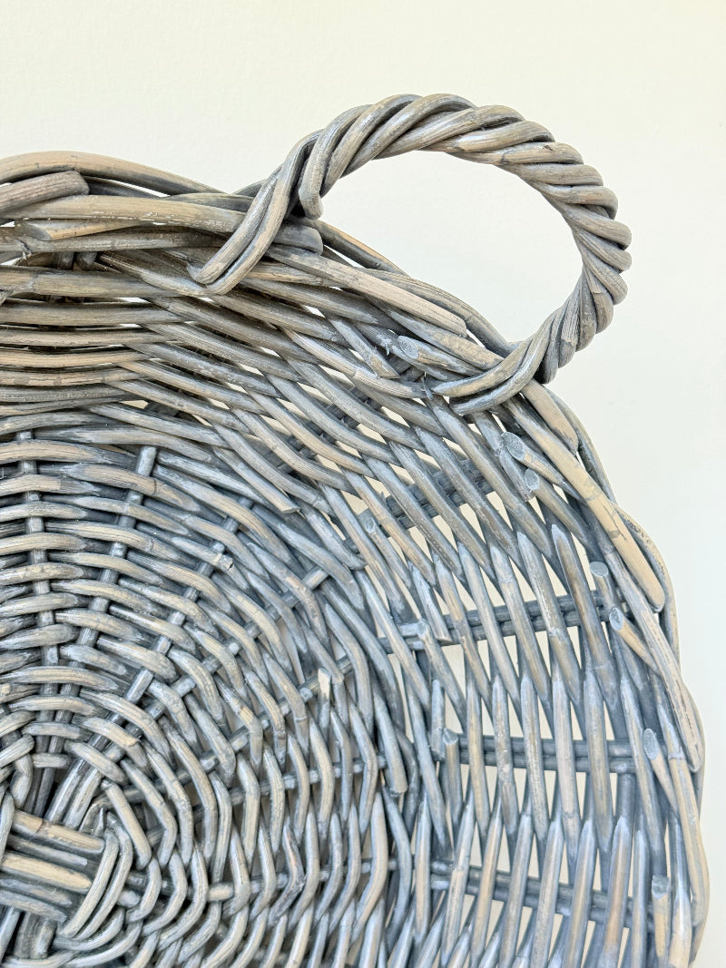 Large vintage woven basket with handles, photographed on a white surface