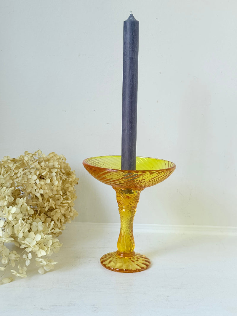 Amber pressed glass candle holder or compote with swirl design and pedestal base, photographed on a white background