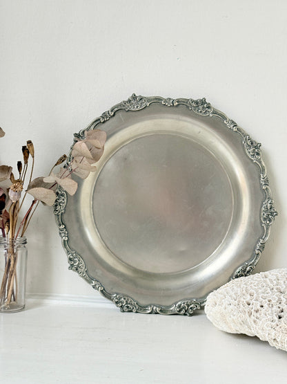 Vintage silvertone metal tray with ornate border, photographed on a white surface