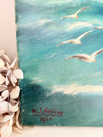 A close-up of a textured canvas painting depicting seagulls flying over turquoise blue water, with a red artist signature reading &