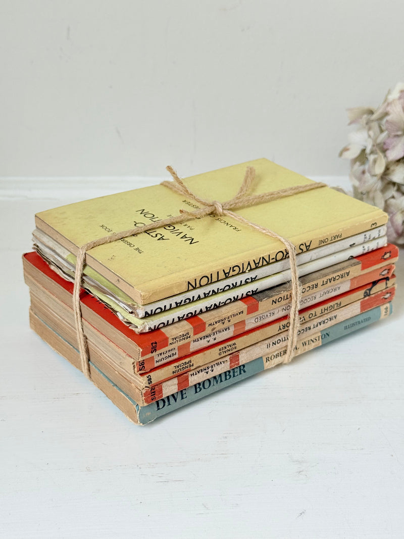 Bundle of vintage Penguin paperback books in orange and cream tones tied with twine, photographed on a white surface