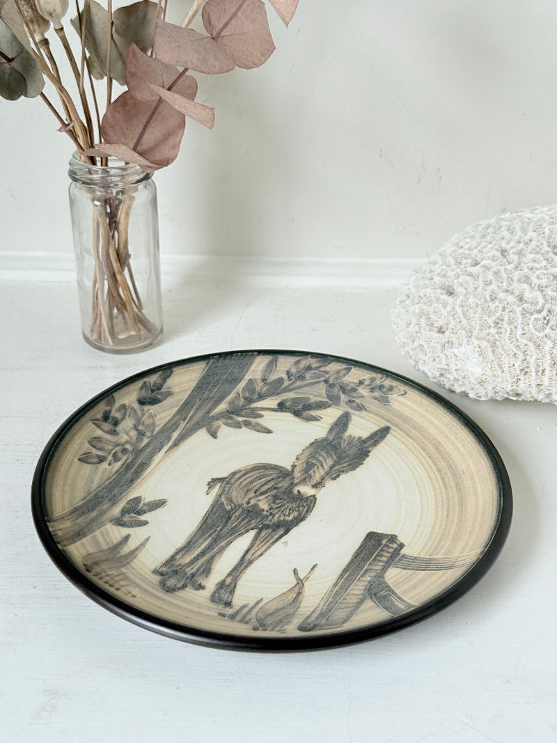 Vintage plate with hand painted brown donkey illustration and dark rim, photographed on a white surface