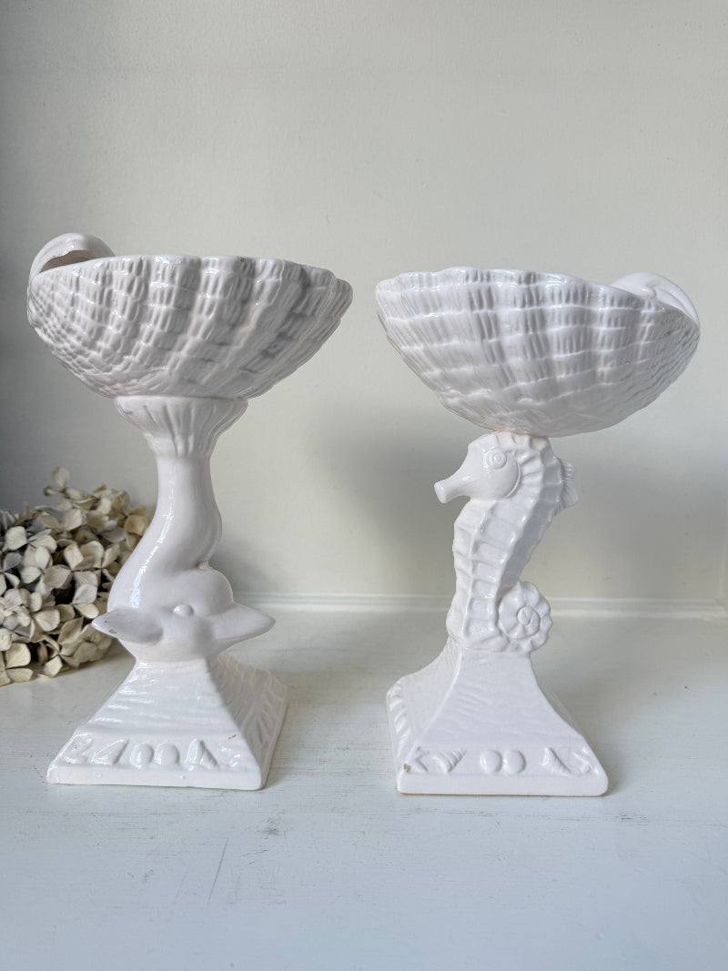 Two white ceramic decorative bowls with seahorse-shaped pedestals, displayed on a white surface against a light neutral background.