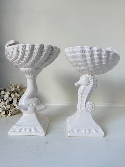 Two white ceramic decorative bowls with seahorse-shaped pedestals, displayed on a white surface against a light neutral background.