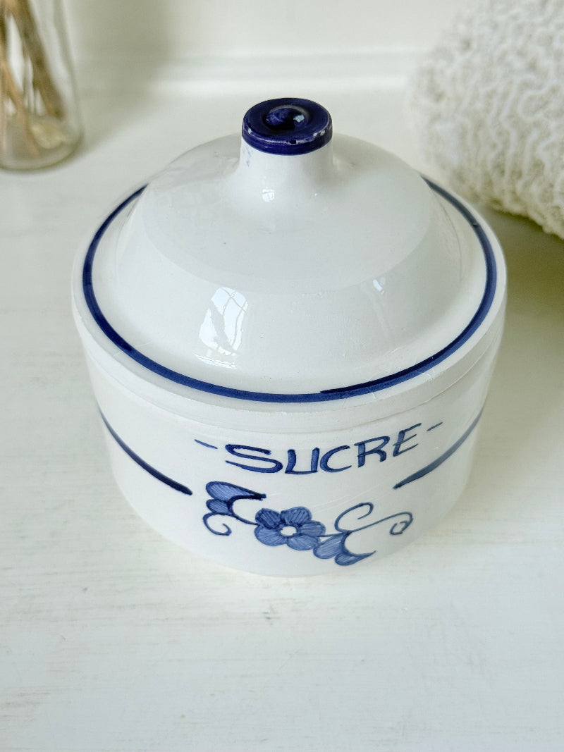 Vintage French blue and white studio pottery sugar bowl with lid, photographed on a white surface.