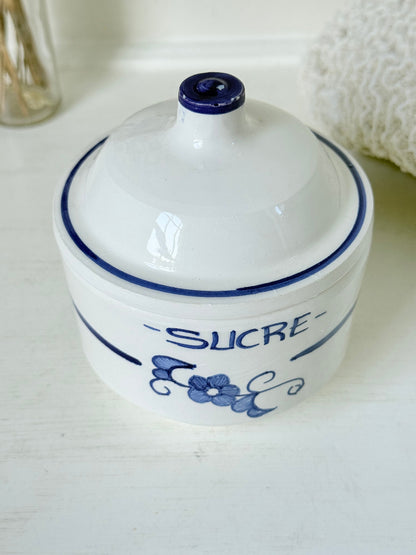 Vintage French blue and white studio pottery sugar bowl with lid, photographed on a white surface.