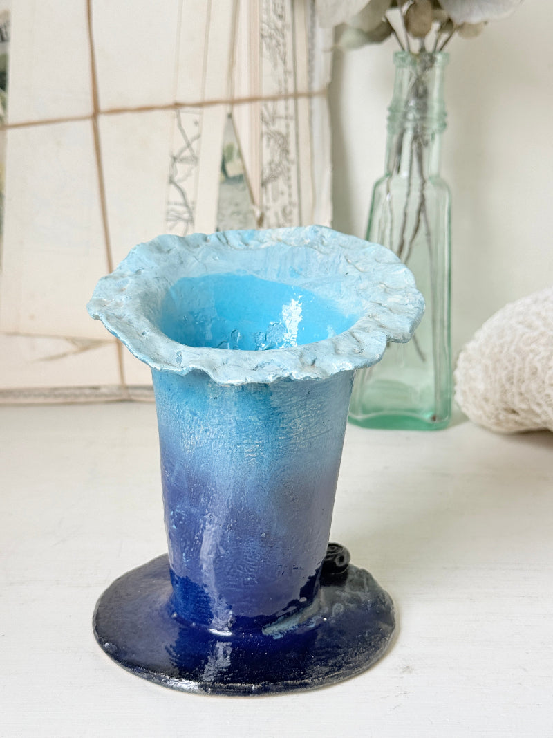 Handmade studio pottery trumpet vase in ombre blue with a frilled rim, photographed on a white surface
